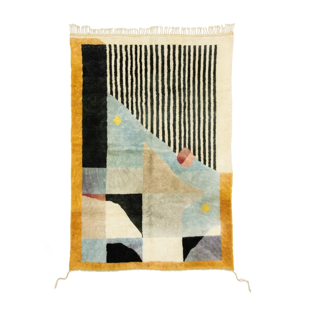 Abstract geometric rug with a mix of black, white, yellow, blue, and beige colors. Design includes stripes, triangles, and rectangles with fringe on top edge.