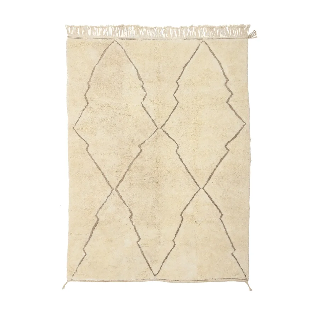 A beige rug with fringe on one end, featuring a geometric brown diamond pattern in the center.