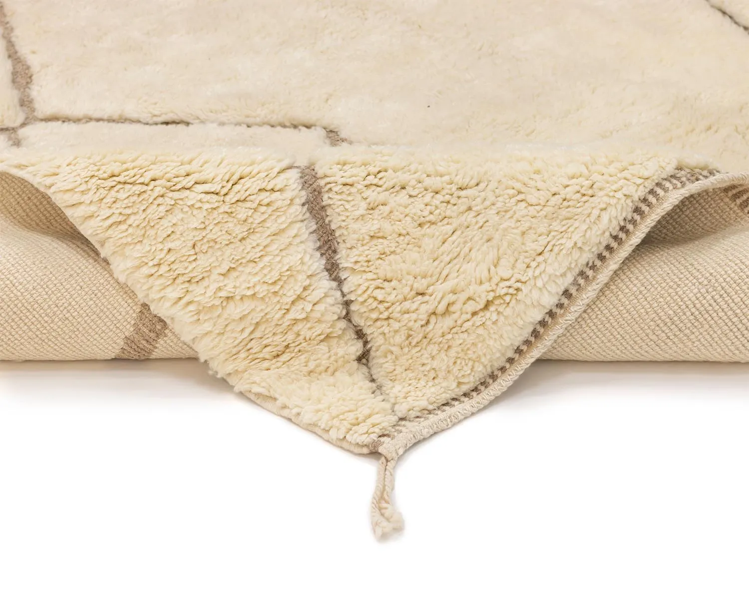 A folded cream-colored, fluffy rug with a beige fringe is shown on a white background.