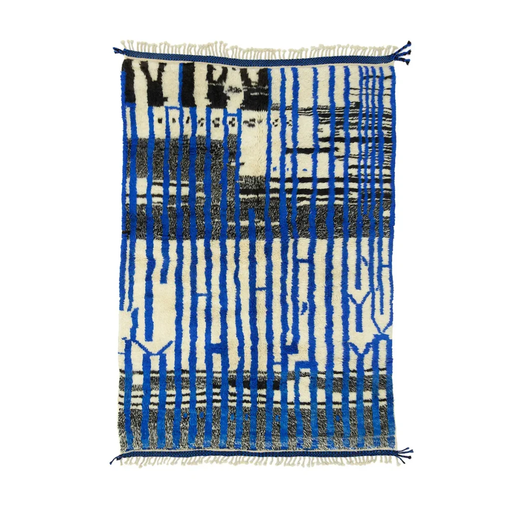 A rectangular rug with abstract patterns in blue, black, and white. The design includes vertical and horizontal lines with fringed edges.