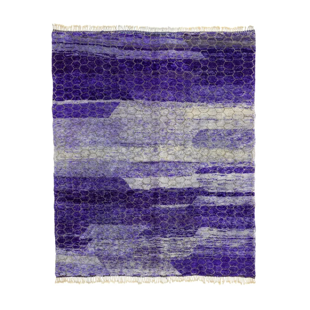 A rectangular rug with abstract patterns in shades of purple, lavender, and gray. It features textured designs and fringed edges.