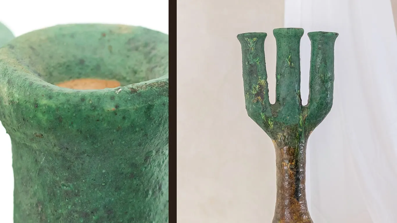 Close-up of a green ancient weapon resembling a trident with aged, textured surface, shown from two angles.