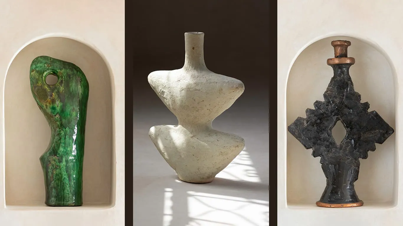 Three abstract ceramic sculptures displayed in individual alcoves: a green curvy form, a white geometric vase, and a dark textured piece with angular shapes.