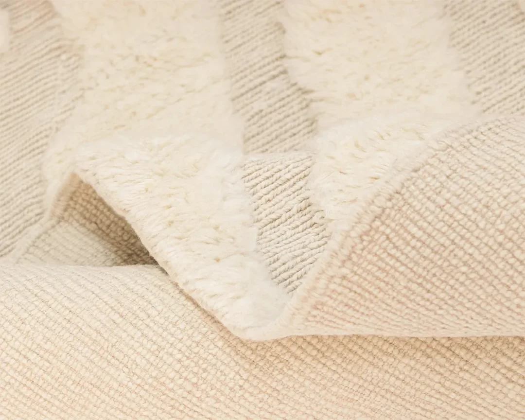 Close-up of a cream-colored textured fabric with alternating soft, fluffy and woven, ribbed sections.
