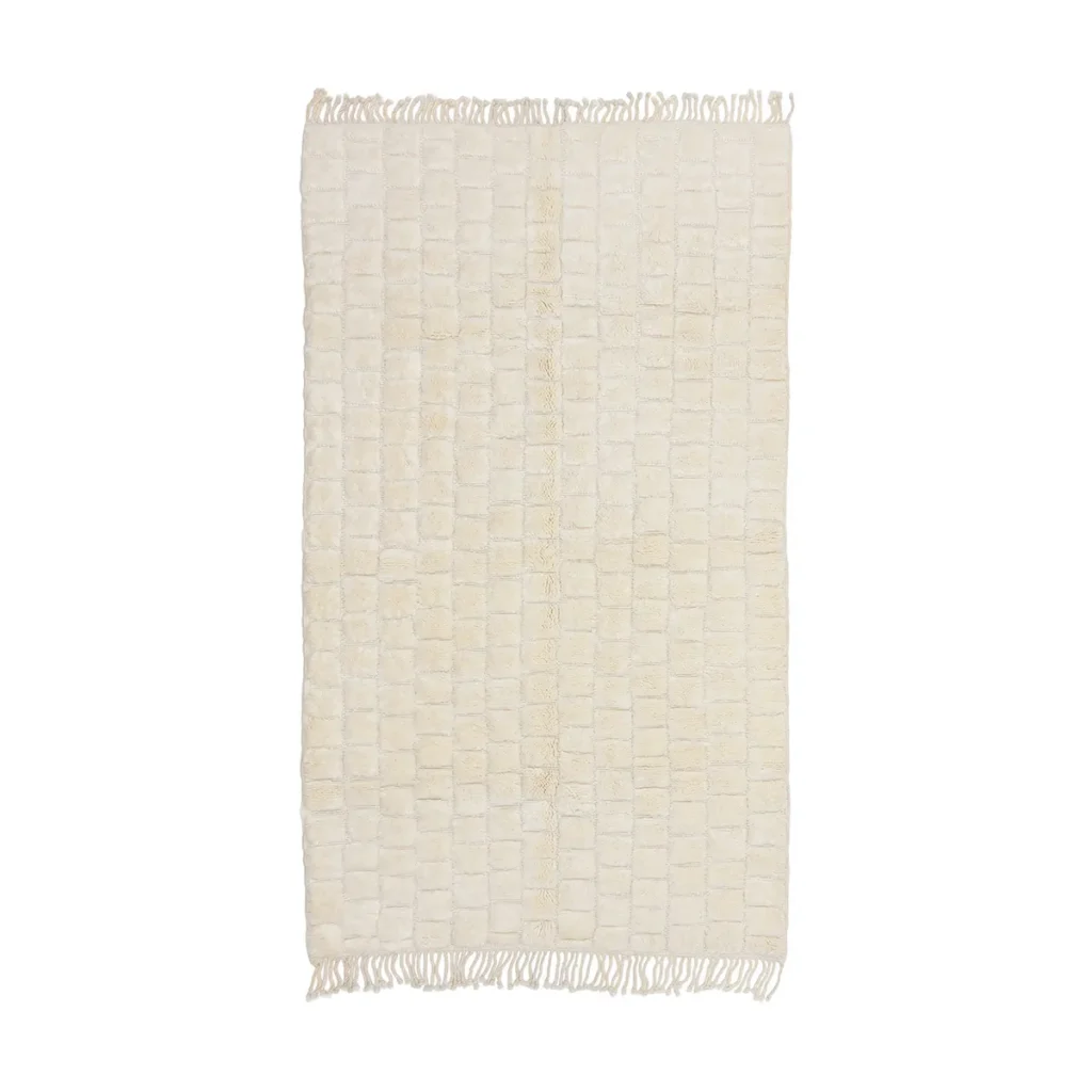 A rectangular, cream-colored rug with a square grid pattern and short fringe on the shorter edges.