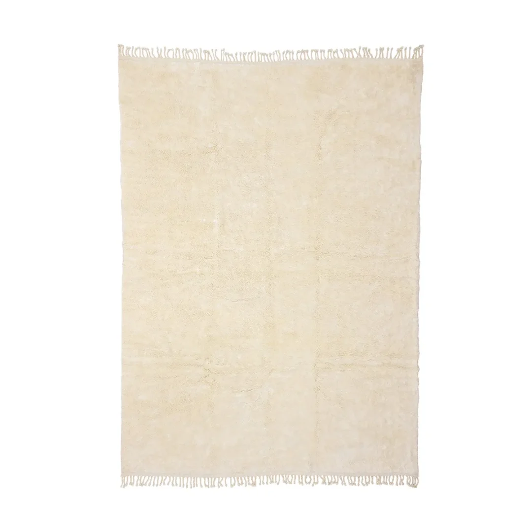 A rectangular, cream-colored rug with a slightly textured surface and fringed edges on both shorter sides.