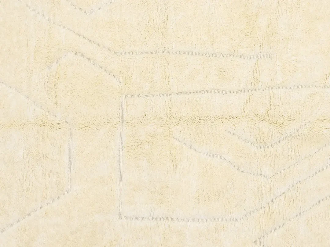 A close-up of a beige textured fabric surface with faint geometric line patterns.