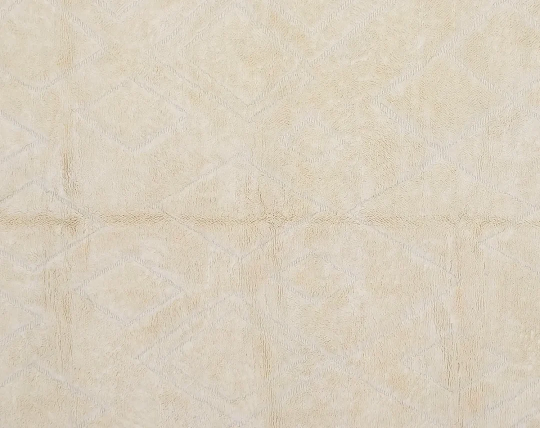 Close-up of a beige fabric surface with a subtle geometric diamond pattern and visible texture.