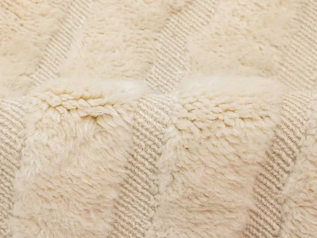Close-up of a cream-colored, textured rug with a soft, plush surface and subtle striped pattern.