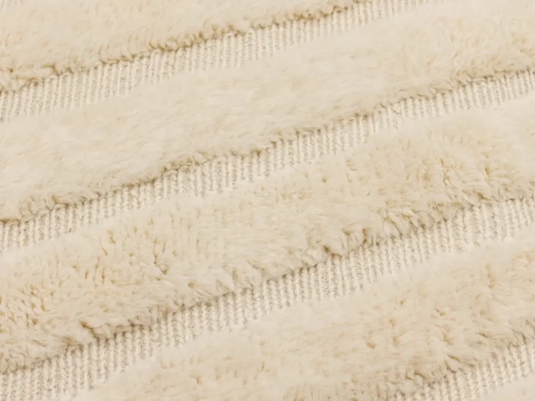 Close-up of a textured cream-colored fabric with alternating plush and flat woven stripes.