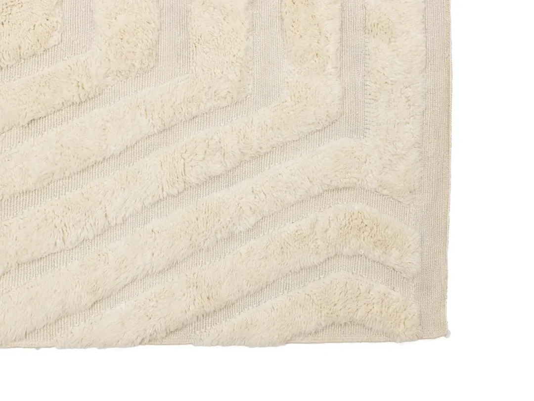 Close-up of a cream-colored textured rug with raised, zigzag geometric patterns.