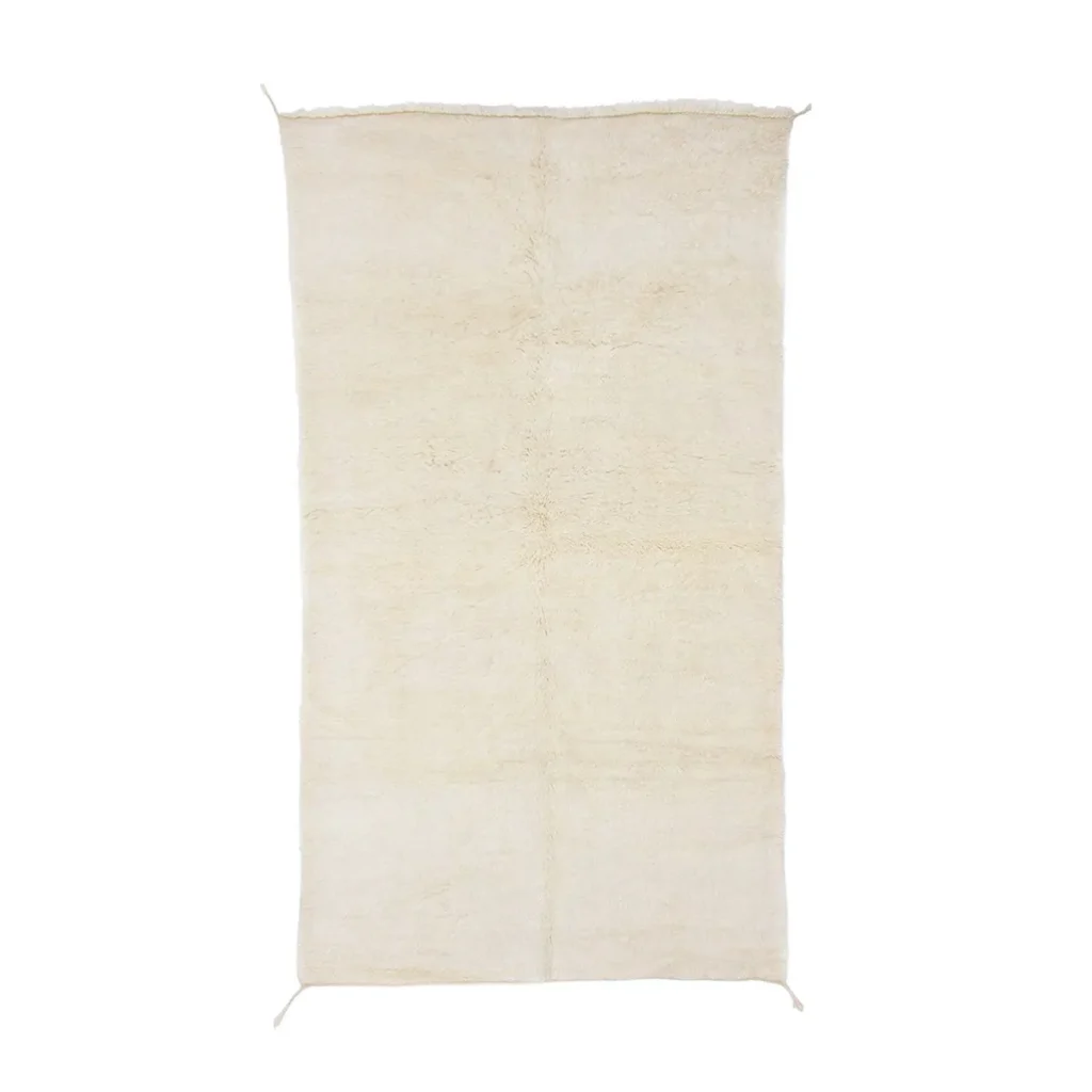 A rectangular, cream-colored shag rug with a slightly uneven edge and a soft, plush texture.