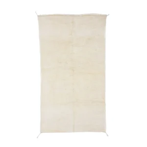 A rectangular, cream-colored shag rug with a slightly uneven edge and a soft, plush texture.