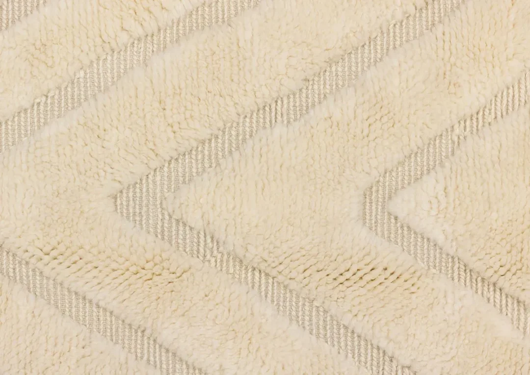 Close-up of a beige textured fabric with a zigzag pattern created by alternating smooth and fluffy sections.
