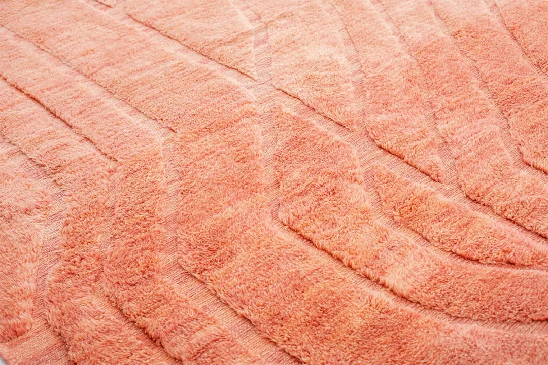 Close-up of a textured, soft, peach-colored fabric with raised, curved patterns.