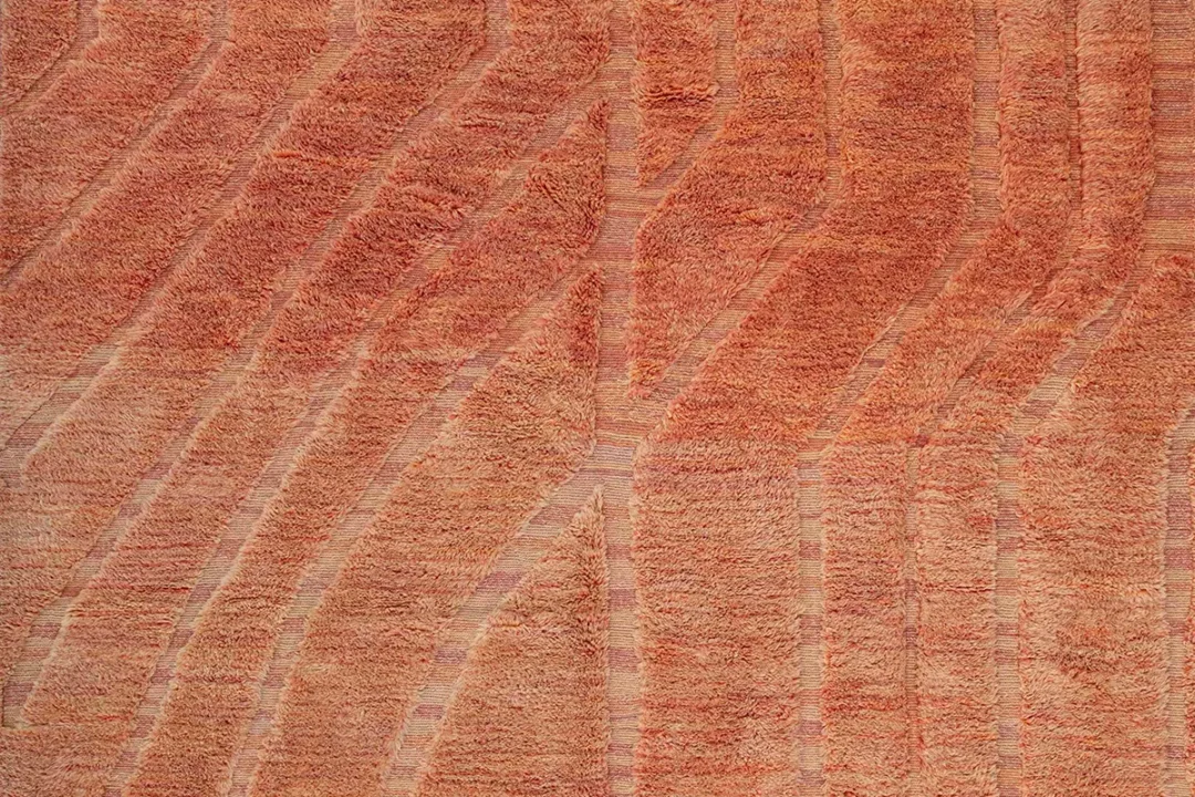 Close-up of an orange and tan textured surface with wavy, irregular lines running vertically, resembling wood grain or sediment layers.