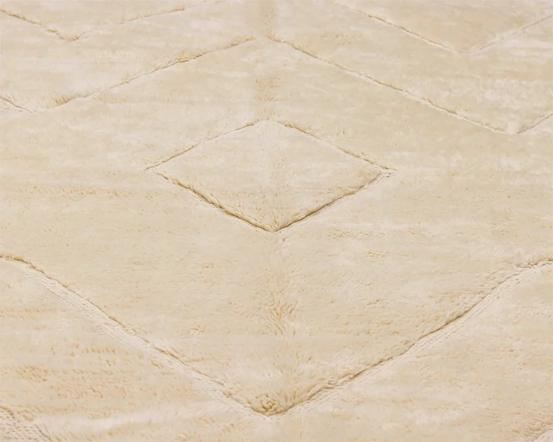 A close-up of a beige, textured fabric with a raised diamond pattern.