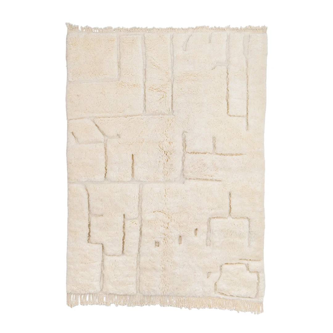 A rectangular off-white rug with a textured, geometric pattern and fringe on both shorter edges, photographed on a white background.
