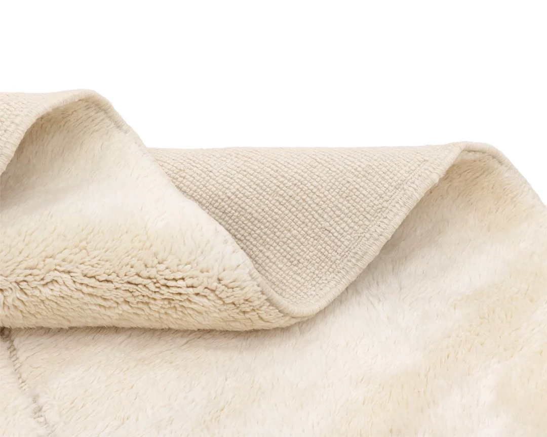 Close-up of a beige blanket showing a soft, plush side and a textured woven side.