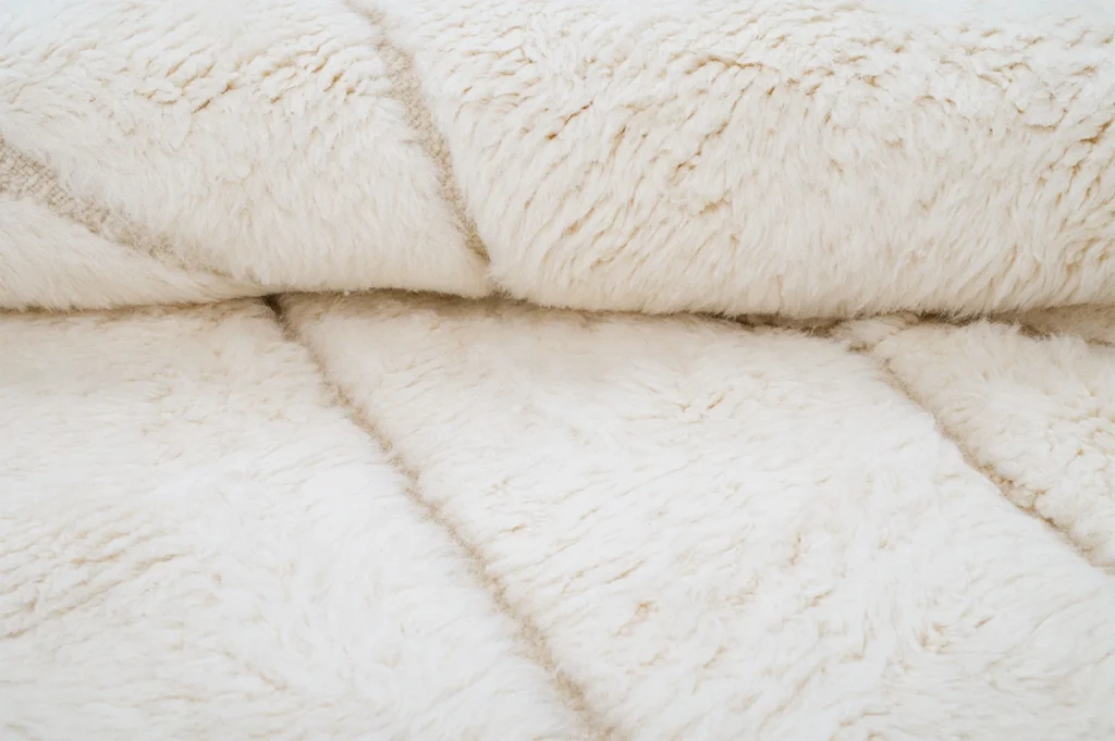 Close-up view of a soft, cream-colored, fluffy rug with a plush texture.
