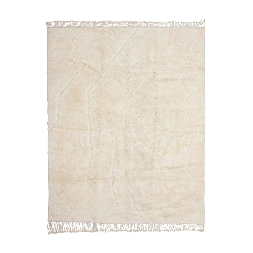 A rectangular, cream-colored shaggy rug with subtle geometric line patterns and fringes along the shorter edges, photographed on a white background.