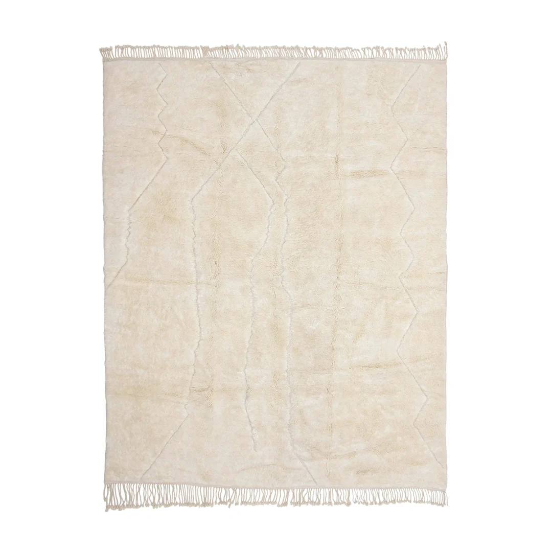 A rectangular, cream-colored shaggy rug with subtle geometric line patterns and fringes along the shorter edges, photographed on a white background.