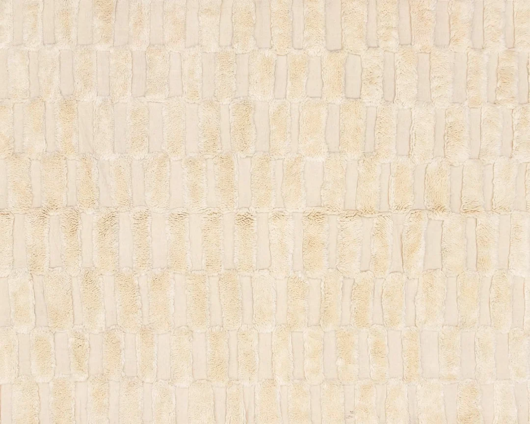 Close-up of a beige, textured Rug with a repeating rectangular pattern, resembling a grid of soft, raised blocks.