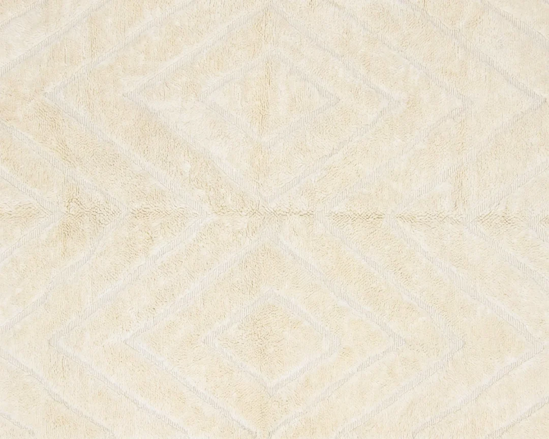 Beige textured surface with a subtle diamond-shaped geometric pattern, likely part of a carpet or rug.