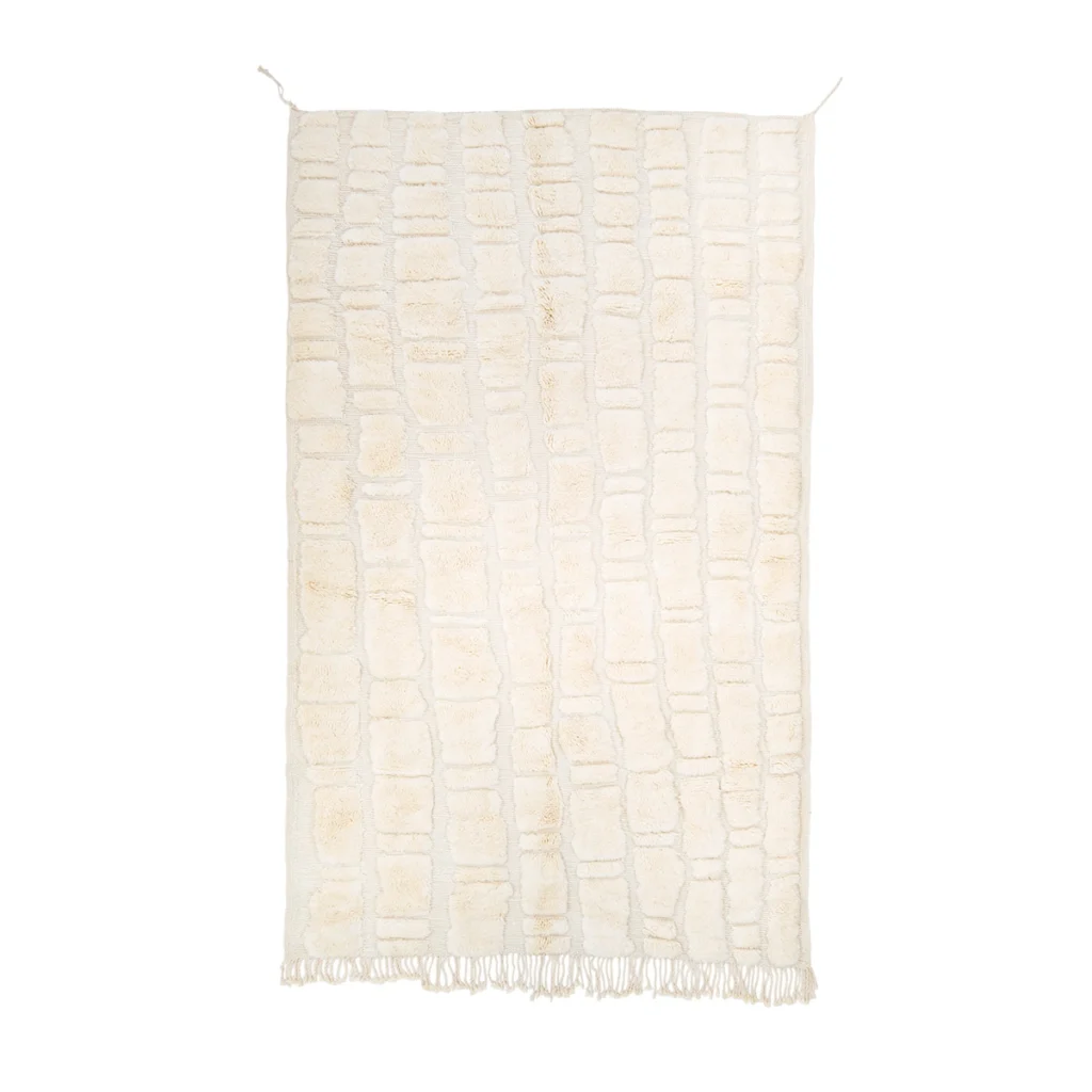 A rectangular cream-colored rug with a textured, irregular grid pattern and short fringe on the bottom edge.
