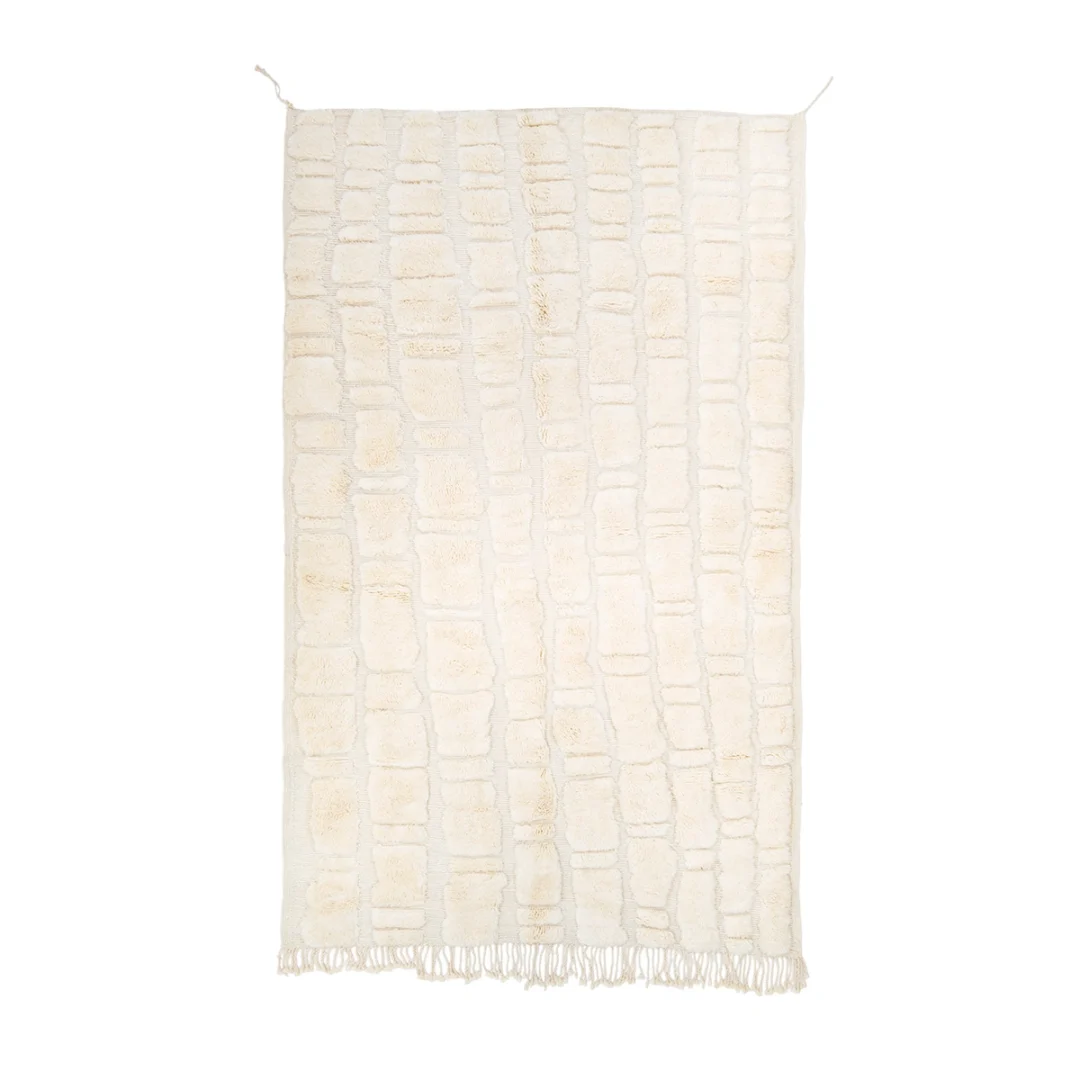 A rectangular cream-colored rug with a textured, irregular grid pattern and short fringe on the bottom edge.