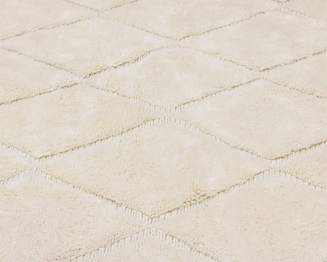 Close-up of a beige, textured carpet with a diamond pattern formed by slightly raised stitching.