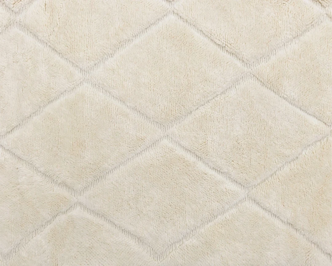 Close-up of a beige, textured fabric with a diamond-shaped quilted pattern.