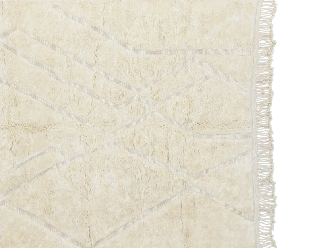 Beige rug with a subtle diamond pattern and fringed edges on the right side.