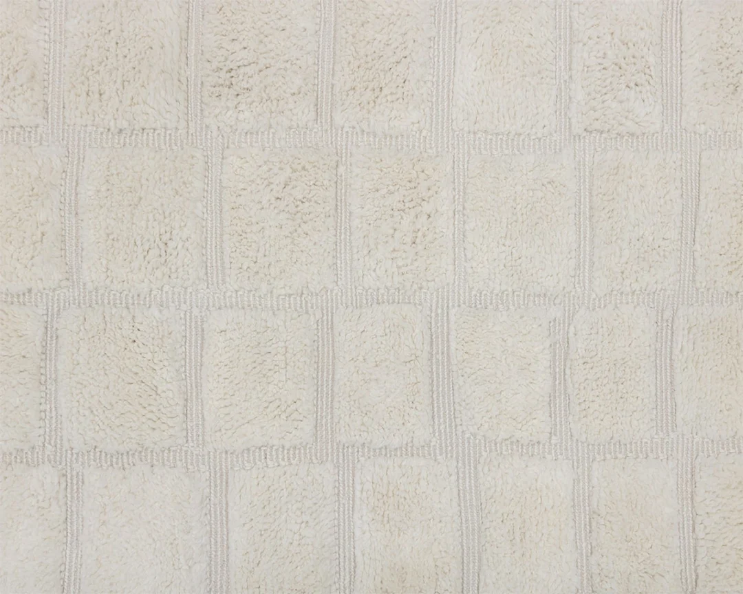 Close-up of a textured beige rug with a geometric square pattern.
