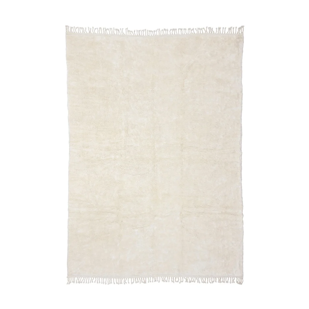 A rectangular, off-white area rug with a soft texture and fringes on the shorter edges, viewed from above against a white background.