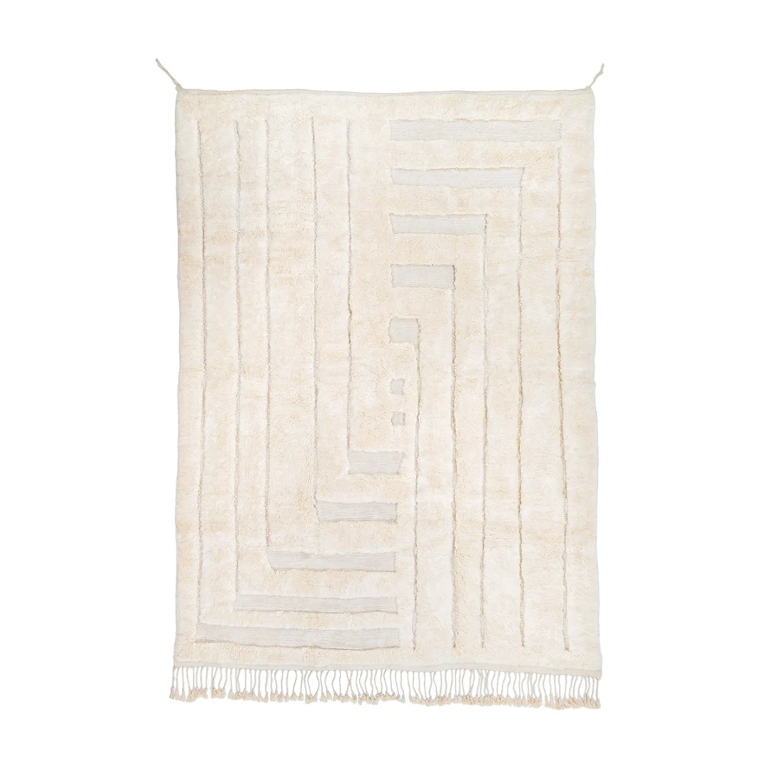 A rectangular cream-colored rug with geometric line patterns and short fringe along the bottom edge, hanging against a white background.