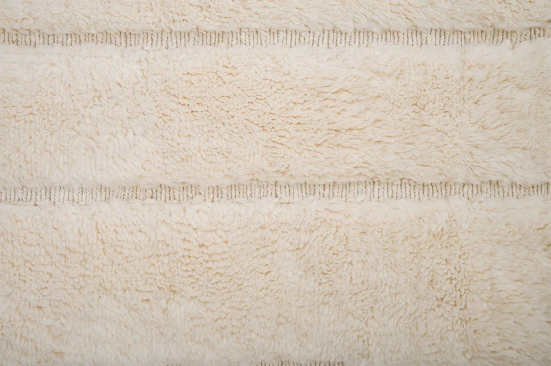 Close-up of a cream-colored, textured rug with horizontal decorative lines.