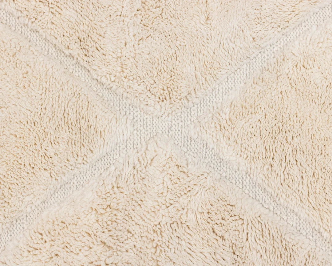 Close-up of a textured, cream-colored fabric with a diamond pattern formed by intersecting lines.