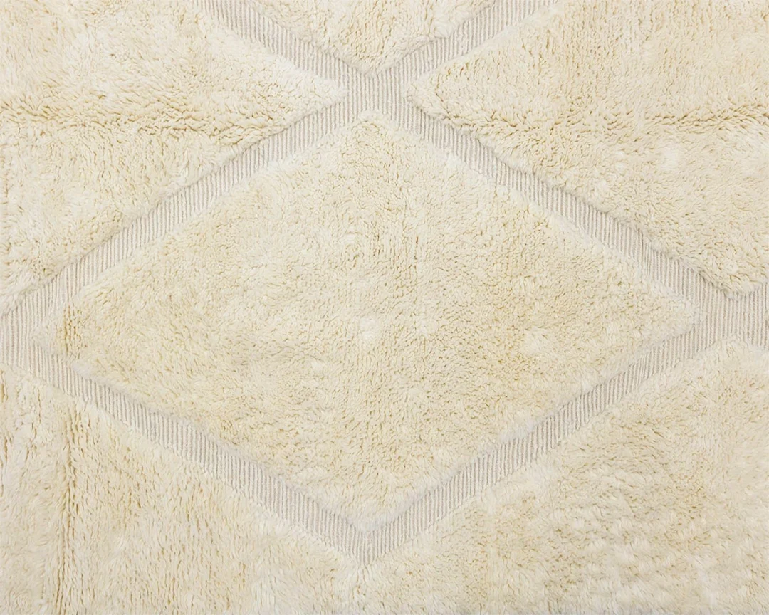 Beige textured surface with a diamond-shaped geometric pattern and soft, fluffy appearance.
