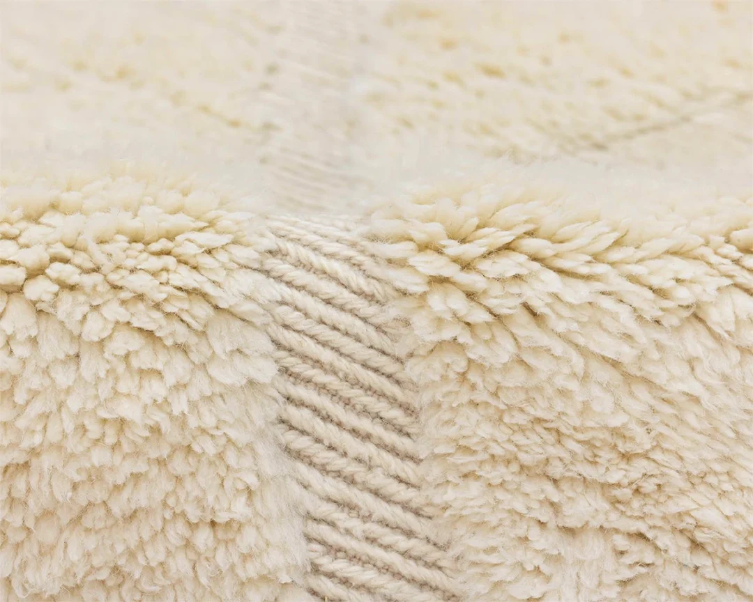 Close-up of a soft, cream-colored textured fabric with thick, fluffy fibers and a subtle diagonal woven pattern.