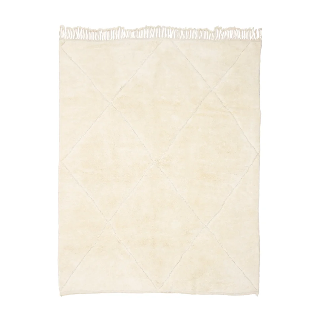 Rectangular cream-colored rug with a subtle diamond pattern, fringe on one edge, and a soft texture.