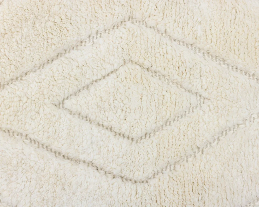 Close-up of a cream-colored, textured wool rug with a raised diamond pattern.