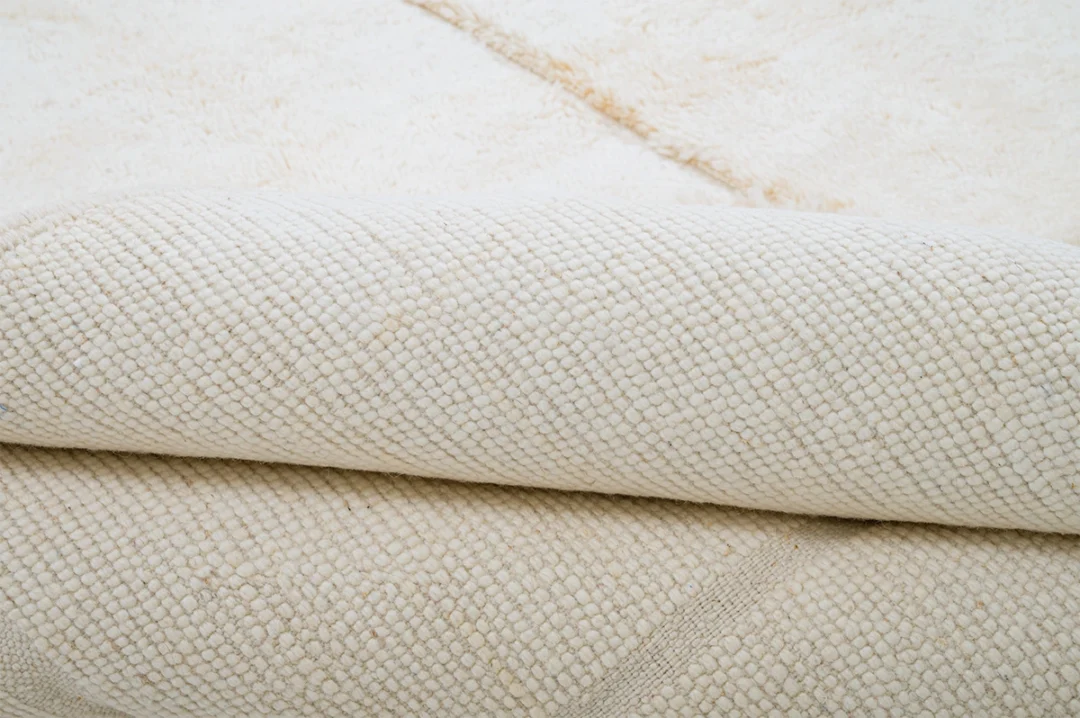Close-up of a folded cream-colored textured fabric with a woven pattern and a soft, plush surface.