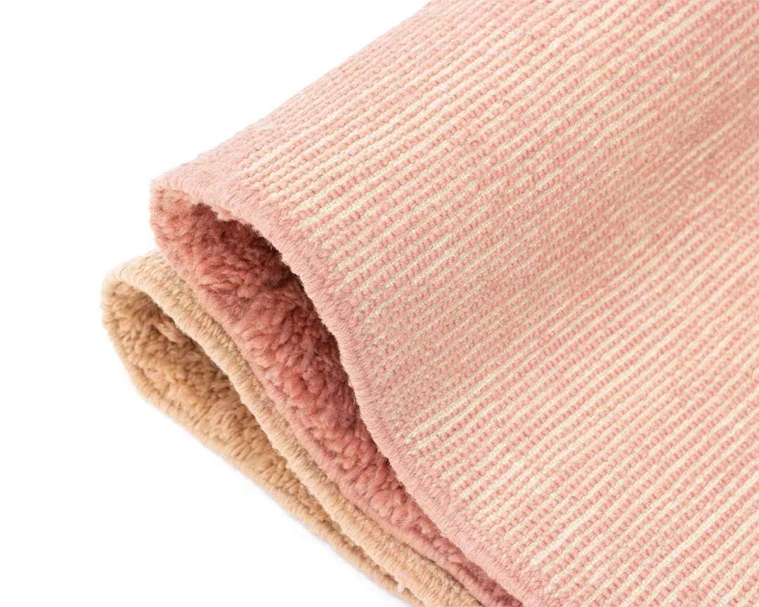 A folded, textured pink and beige fabric with a ribbed outer surface and a soft, fleece-like inner layer.