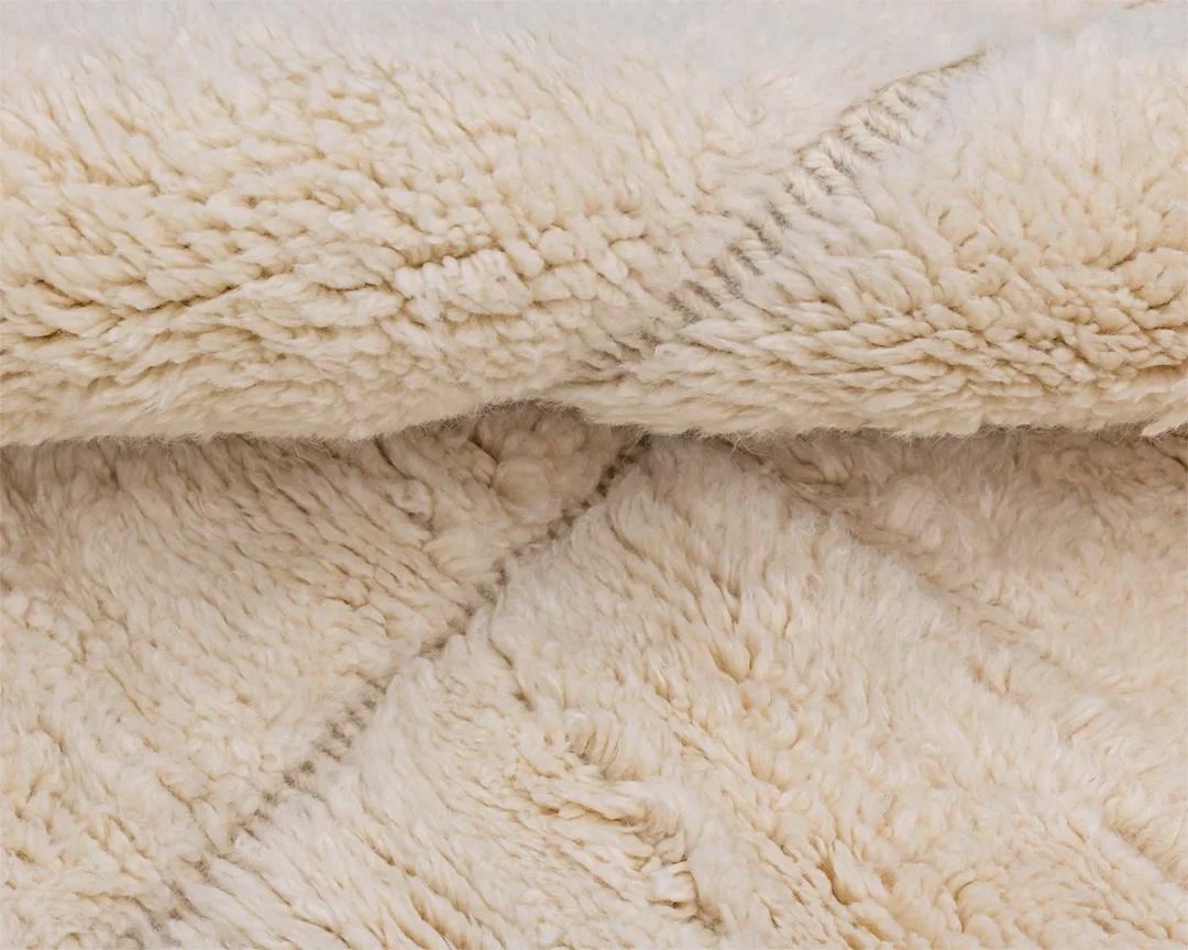Close-up of a soft, cream-colored, fluffy fleece fabric with a visible diagonal seam pattern.