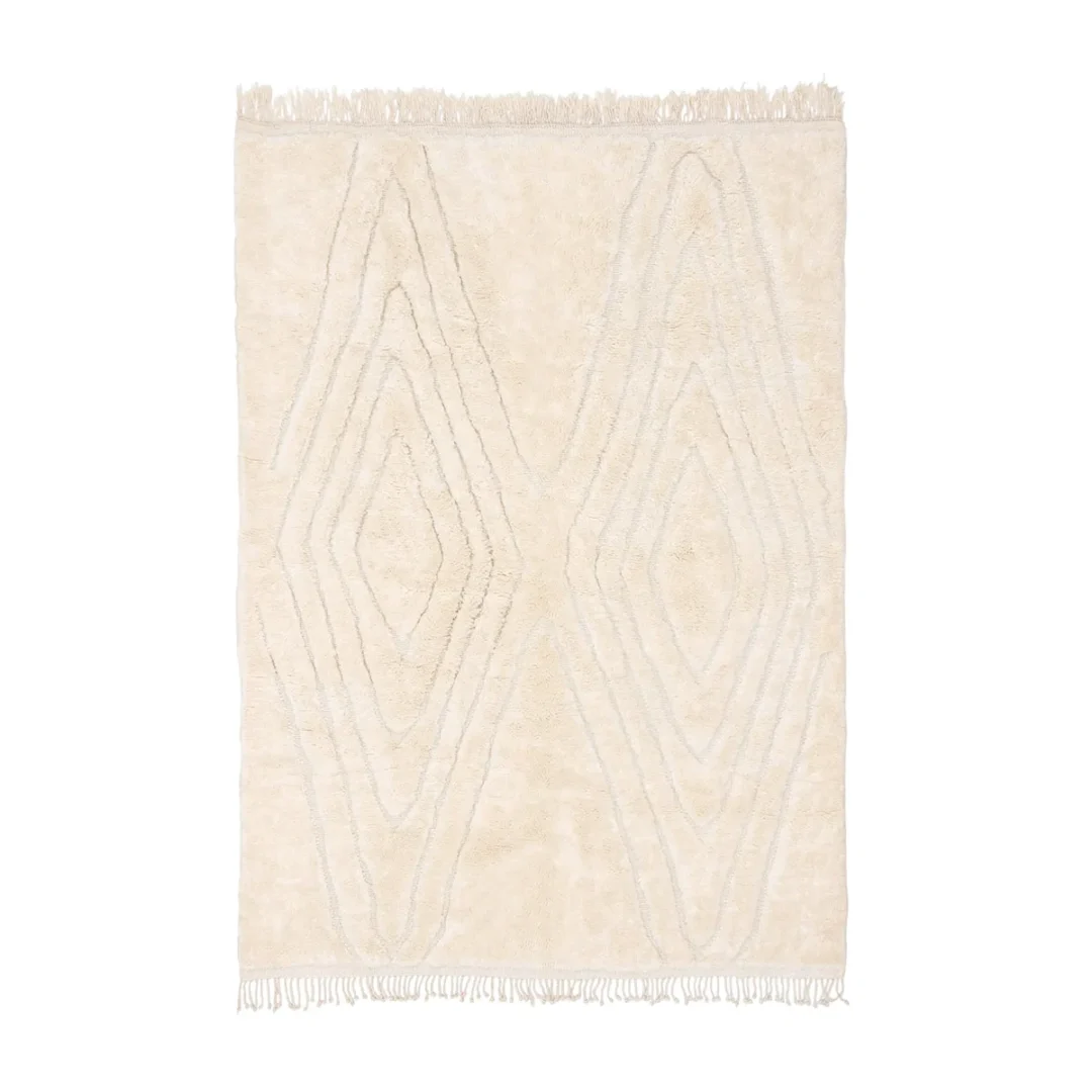 A rectangular beige rug with a subtle geometric diamond pattern and fringed edges on the shorter sides.
