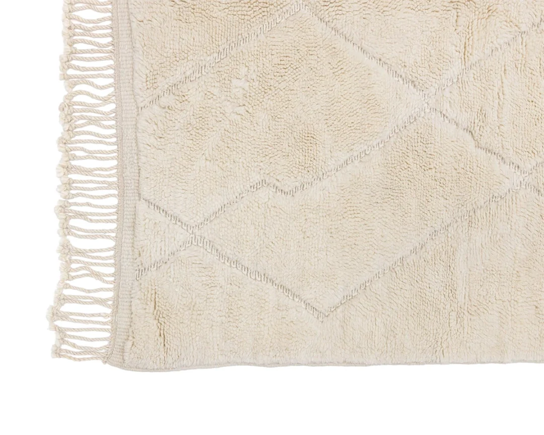 A beige rug with a subtle diamond pattern and fringe along the edge.
