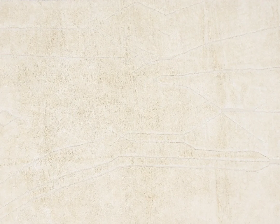A cream-colored textured surface with faint, irregular lines and subtle geometric patterns.