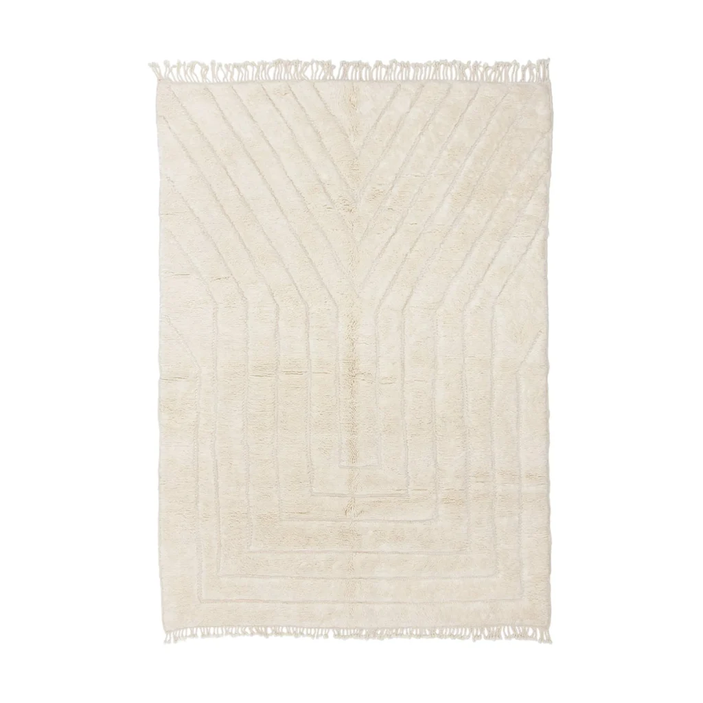 A cream-colored rectangular rug with a subtle geometric pattern and fringe on the shorter edges.