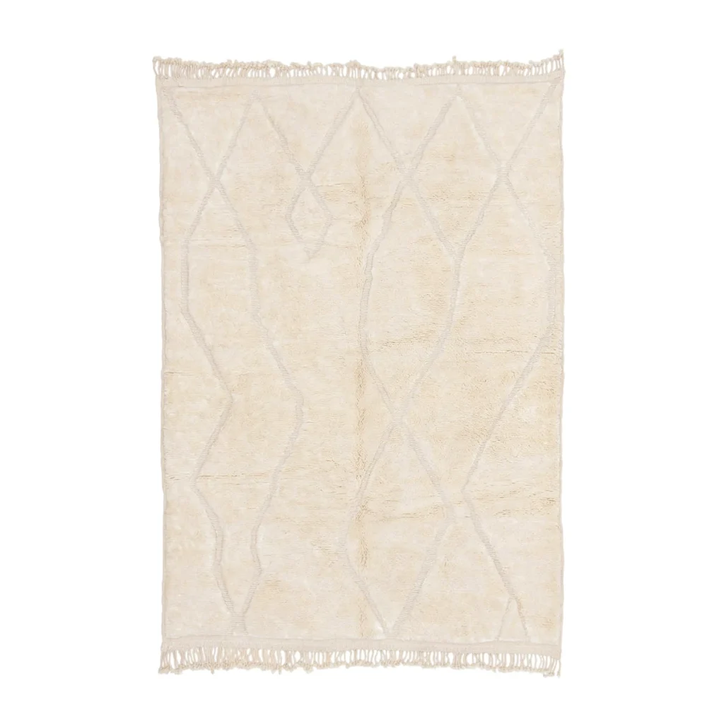 A cream-colored area rug with a subtle, irregular geometric pattern and fringed edges on the shorter sides.